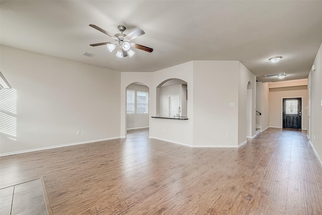 unfurnished living room featuring light wood-style floors, ceiling fan, plenty of natural light, and visible vents
