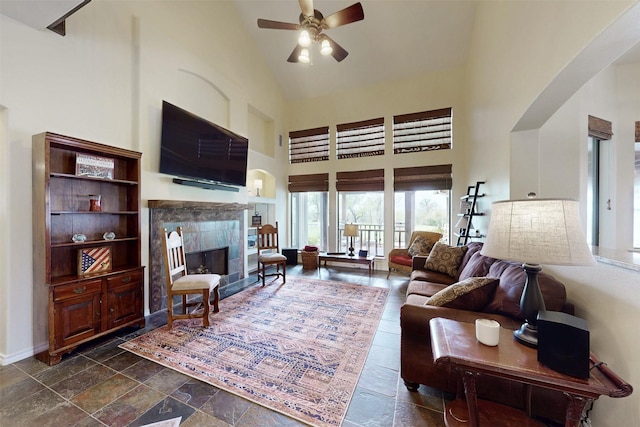 7576 River Ridge Drive, College Station, TX 77845 - living room with stone tile flooring, a fireplace, ceiling fan, high vaulted ceiling, and arched walkways