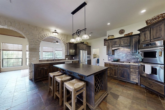 7576 River Ridge Drive, College Station, TX 77845 - kitchen with washer and dryer, stainless steel appliances, stone tile floors, and backsplash