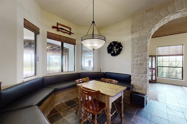 7576 River Ridge Drive, College Station, TX 77845 - dining space with stone tile flooring, arched walkways, decorative columns, and a healthy amount of sunlight