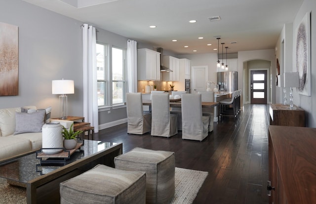 living room with arched walkways, visible vents, dark wood-style floors, and recessed lighting