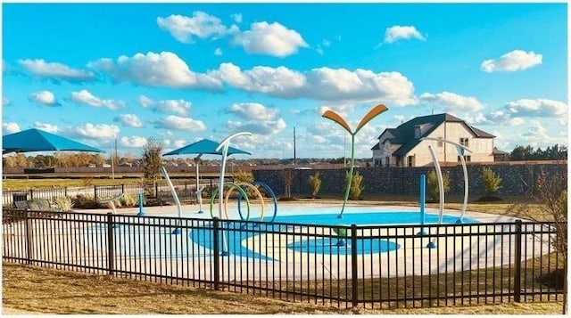 view of swimming pool with a swimming pool, fence, and playground community