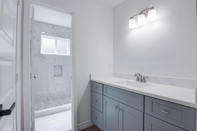 full bath with a marble finish shower and vanity