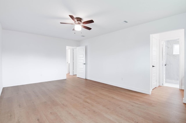 empty room with light wood-style floors, a ceiling fan, baseboards, and visible vents