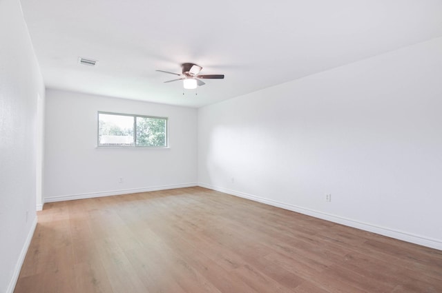 spare room with light wood-style floors, baseboards, ceiling fan, and visible vents