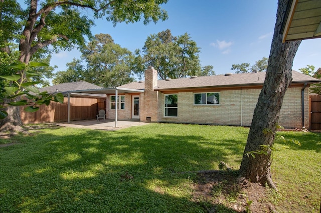 rear view of house featuring fence, a chimney, brick siding, a patio area, and a lawn