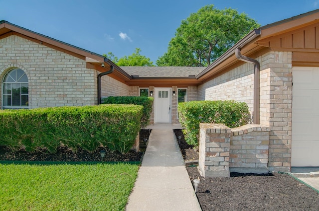 view of exterior entry with a garage and brick siding