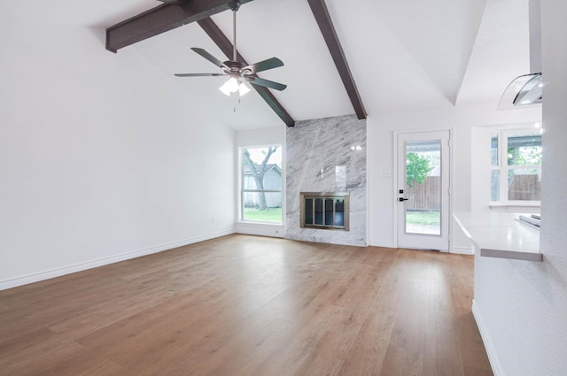 unfurnished living room with baseboards, wood finished floors, and beamed ceiling