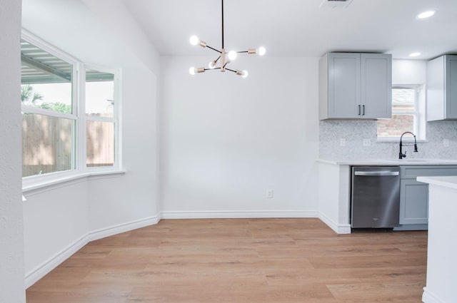 kitchen with a sink, light wood finished floors, a chandelier, and dishwasher