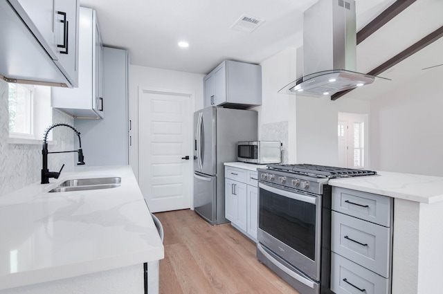 kitchen featuring exhaust hood, light stone counters, a sink, light wood-style floors, and stainless steel appliances
