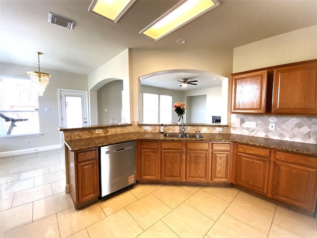kitchen featuring stainless steel dishwasher, visible vents, a sink, arched walkways, and brown cabinets