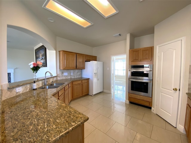 kitchen with white fridge with ice dispenser, a sink, stainless steel double oven, visible vents, and backsplash