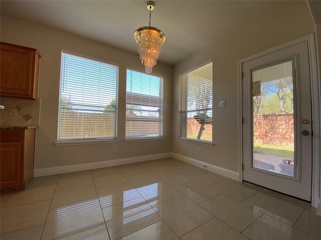 unfurnished dining area featuring light tile patterned flooring, baseboards, and a notable chandelier