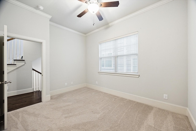 unfurnished room featuring carpet floors, a ceiling fan, baseboards, and crown molding