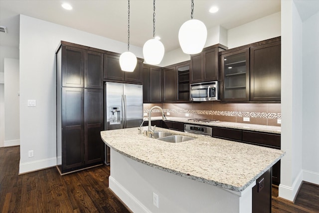 kitchen featuring dark brown cabinets, glass insert cabinets, tasteful backsplash, a sink, and stainless steel appliances