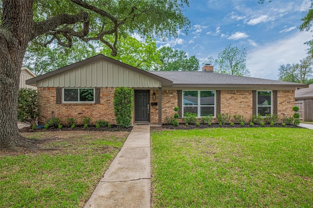 ranch-style house featuring board and batten siding, a chimney, a front yard, and brick siding