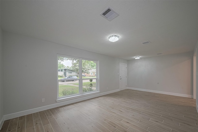spare room featuring baseboards, wood finished floors, and visible vents
