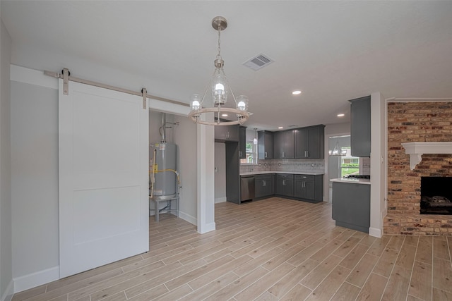 kitchen with a barn door, water heater, baseboards, stainless steel dishwasher, and visible vents