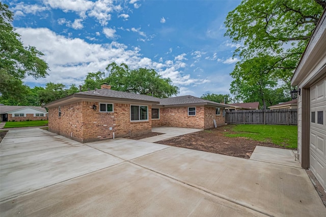 rear view of property with a chimney, a patio area, brick siding, fence, and a yard