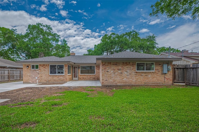view of front of property featuring brick siding, a front yard, fence, and a patio area