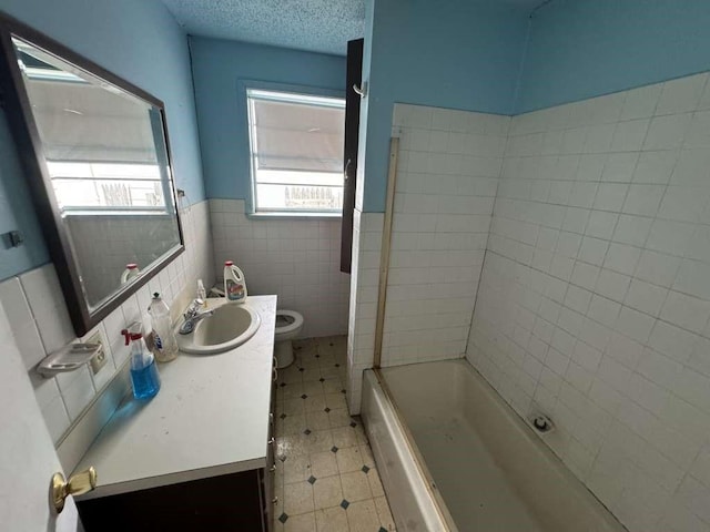 bathroom featuring tile patterned flooring, vanity, wainscoting, toilet, and tile walls