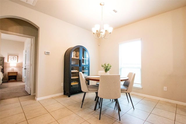 dining area featuring visible vents, baseboards, arched walkways, light tile patterned floors, and a notable chandelier