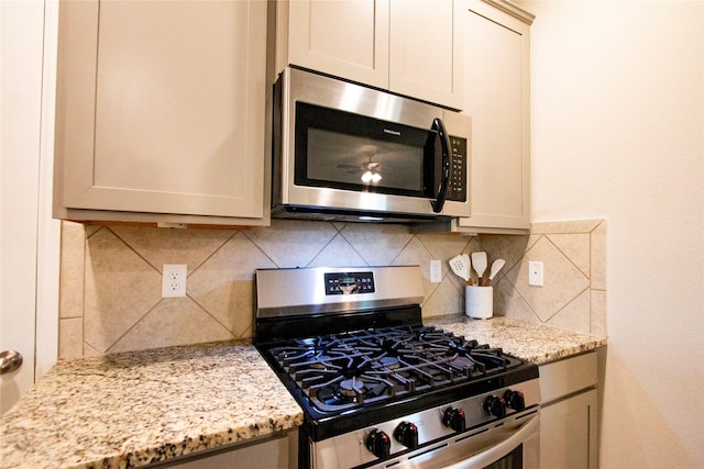 kitchen featuring tasteful backsplash, light stone countertops, and stainless steel appliances