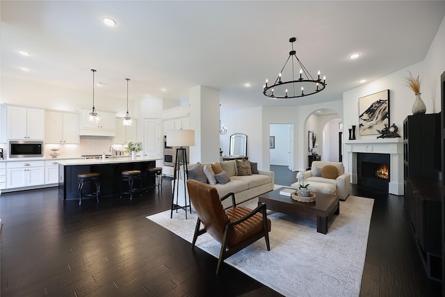 living area featuring arched walkways, an inviting chandelier, dark wood-style floors, and recessed lighting