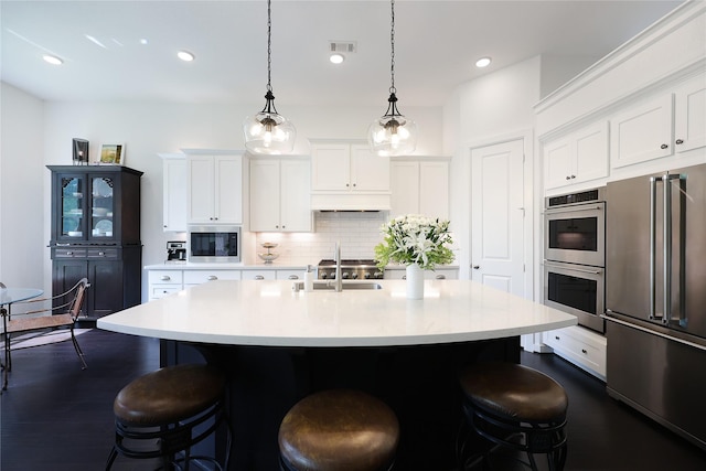 kitchen featuring visible vents, a breakfast bar area, light countertops, backsplash, and stainless steel appliances