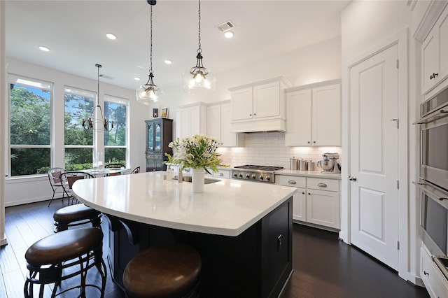 kitchen featuring decorative backsplash, a kitchen breakfast bar, visible vents, dark wood finished floors, and light countertops