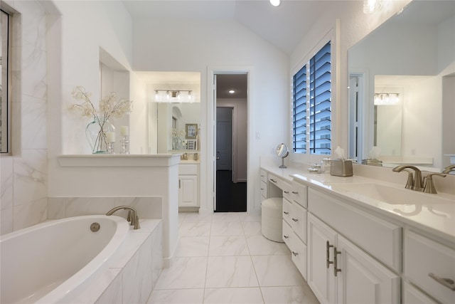bathroom with vanity, a garden tub, marble finish floor, and lofted ceiling