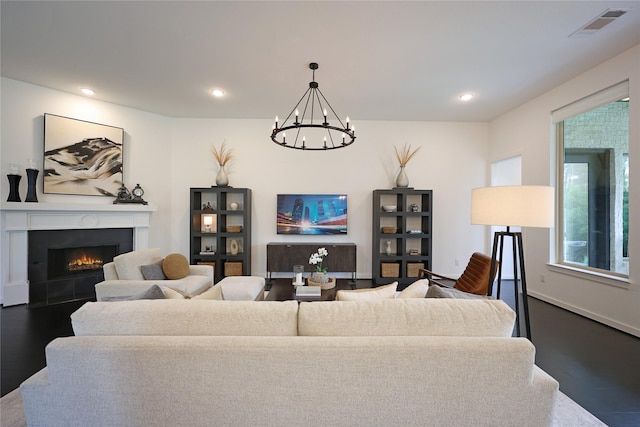 living room featuring visible vents, wood finished floors, a warm lit fireplace, recessed lighting, and a chandelier