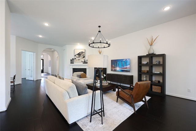 living area with an inviting chandelier, arched walkways, recessed lighting, and dark wood-type flooring
