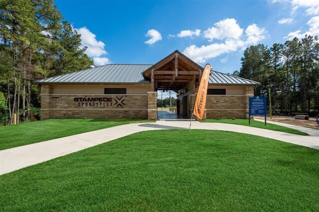 view of front of property featuring a front lawn, brick siding, concrete driveway, a standing seam roof, and metal roof