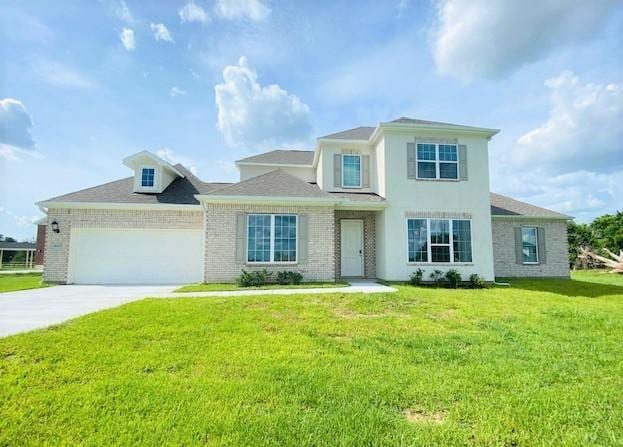 view of front of property with driveway, a garage, brick siding, a front lawn, and stucco siding