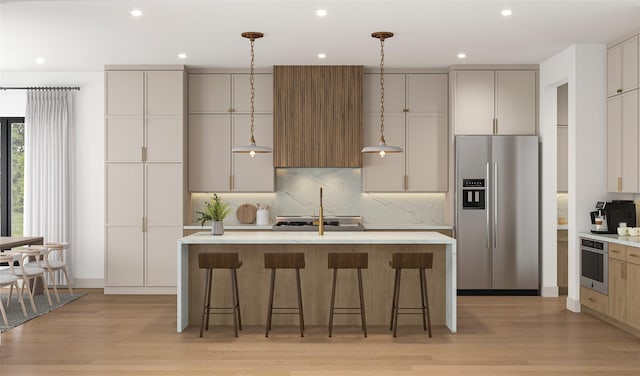 kitchen featuring a center island with sink, appliances with stainless steel finishes, tasteful backsplash, and light wood-style floors