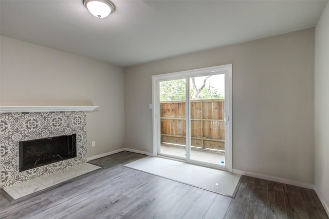 unfurnished living room with baseboards, a fireplace, and wood finished floors