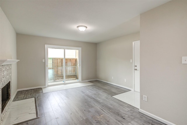 unfurnished living room featuring baseboards, wood finished floors, and a fireplace