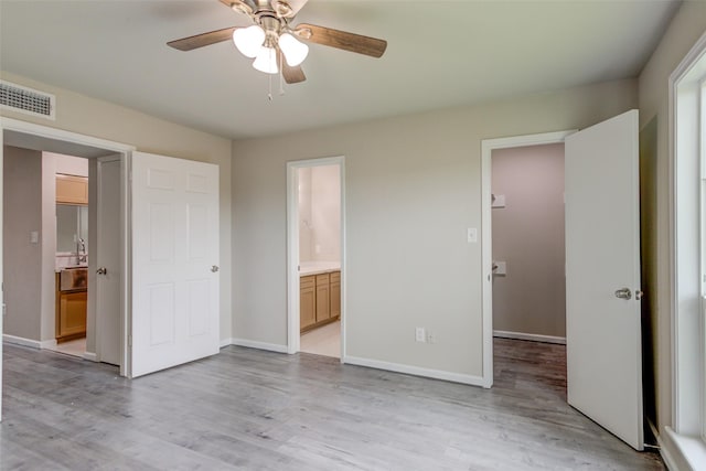 unfurnished bedroom featuring light wood-style floors, baseboards, ensuite bath, and visible vents