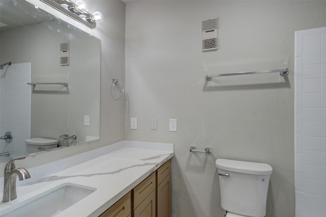 bathroom with vanity, toilet, visible vents, and a shower