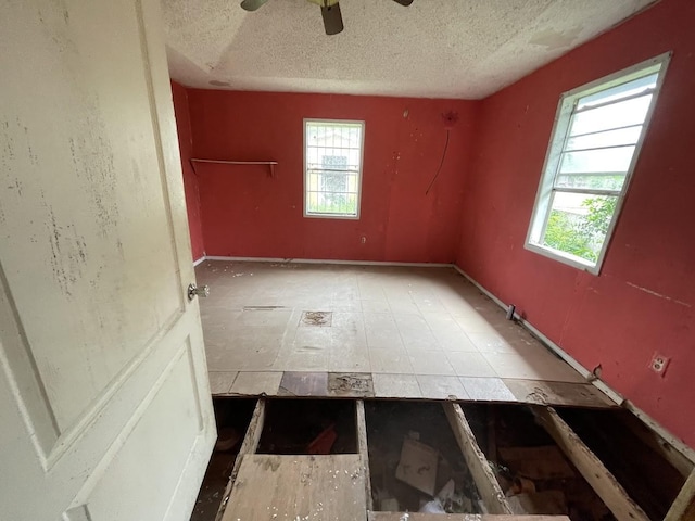 unfurnished room with a textured ceiling, ceiling fan, and a wealth of natural light