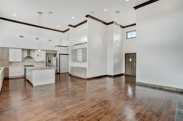 kitchen featuring stainless steel fridge, ornamental molding, a high ceiling, and light countertops