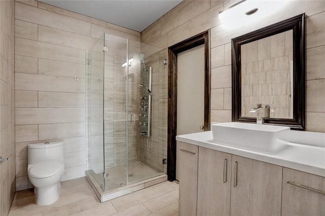 bathroom featuring vanity, toilet, tile walls, tile patterned floors, and a stall shower