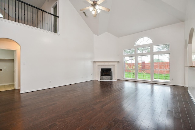 unfurnished living room featuring ceiling fan, visible vents, arched walkways, a tile fireplace, and high vaulted ceiling