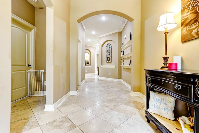 hallway with crown molding, arched walkways, light tile patterned floors, baseboards, and recessed lighting