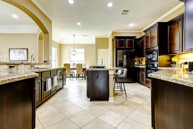 kitchen featuring visible vents, a kitchen bar, a sink, backsplash, and black appliances