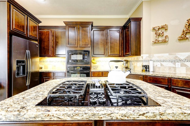 kitchen with backsplash, light stone countertops, and black appliances