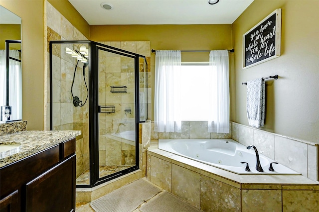 full bathroom featuring vanity, a jetted tub, and a stall shower