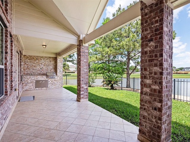 view of patio / terrace featuring fence, a water view, and area for grilling