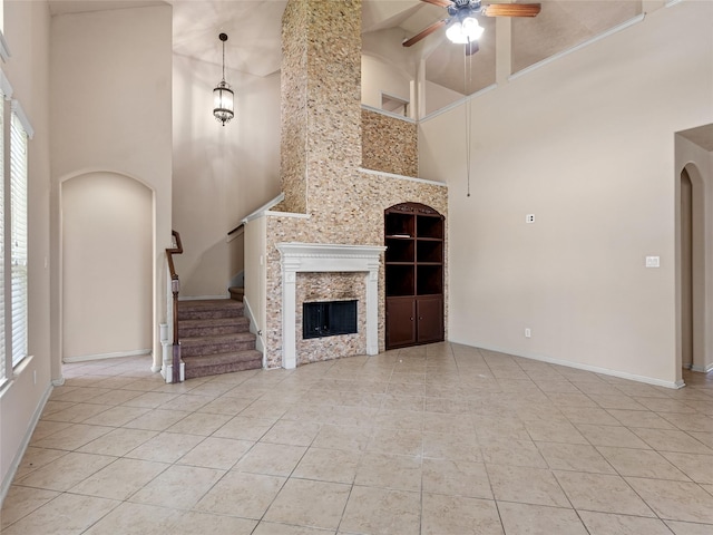 unfurnished living room featuring plenty of natural light, arched walkways, ceiling fan, and a towering ceiling